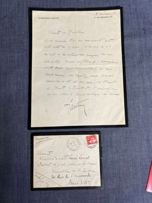 une vieille lettre et une enveloppe, posées sur un tissu bleu, avec une enveloppe rouge par-dessus