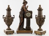 une statue représentant une femme assise sur un socle, à côté de trois vases