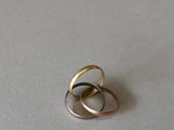 two gold and silver rings sitting on top of a white surface