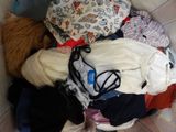 a pile of clothes in a basket with a teddy bear