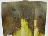 un vase marron et jaune posé sur une surface blanche