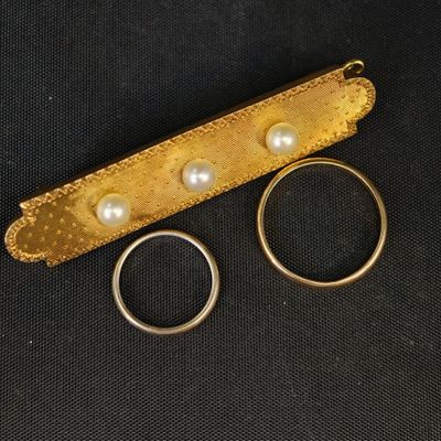 deux alliances en or et une bague en perle sur fond noir
