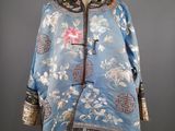 une photo d'une veste bleue ornée de fleurs, posée sur un mannequin