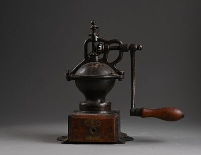 un vieux moulin à café avec un manche en bois sur fond gris