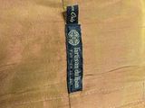 the back of a tan jacket with a black label on it