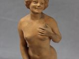 statue of a nude woman holding a vase on a white surface