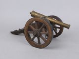 un petit canon en bronze posé sur une roue en bois