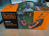 the box is open on the floor with a lawn mower in it