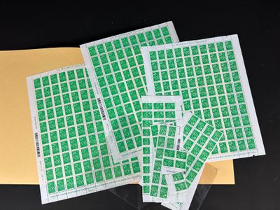 quatre feuilles de timbres verts posées sur une enveloppe jaune
