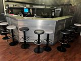 Plusieurs tabourets sont disposés devant un comptoir dans un restaurant