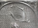 a close up of a silver vase with a bird house on it