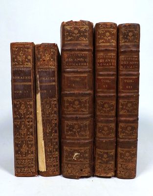 several old books sitting on top of each other on a white surface