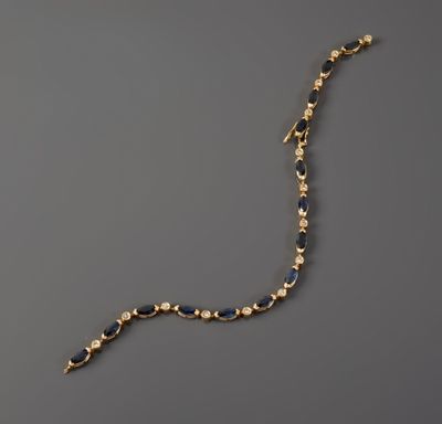a close up of a gold and blue necklace on a gray surface