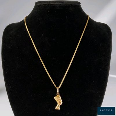 un collier plaqué or avec un pendentif en forme de tête égyptienne, présenté sur un mannequin