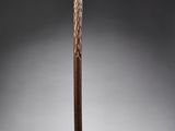 une vieille canne en bois avec un pommeau sculpté sur fond gris