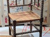 a wooden chair with a woven seat on a rug