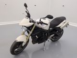 une moto blanche garée dans une pièce au sol gris