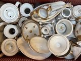 a basket full of white and gold dishes and cups