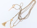 three gold necklaces with tassels and a key on a white background