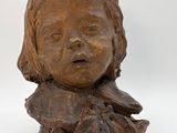 sculpture représentant la tête d'un enfant sur un morceau de bois