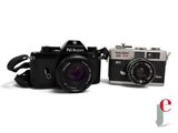 two cameras sitting next to each other on a white surface