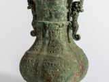 un grand vase vert orné de sculptures sur fond blanc