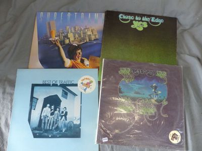 three albums of various music on a bed with a white sheet