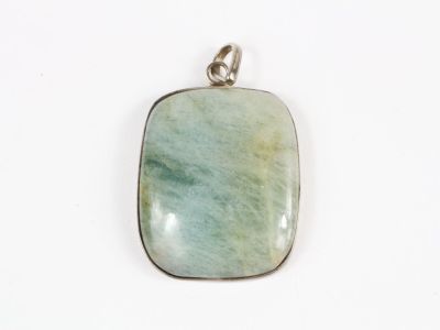 un gros plan d'un pendentif en pierre verte posé sur une surface blanche