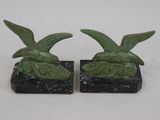 une paire de serre-livres en forme d'oiseaux verts posés sur des socles en marbre noir