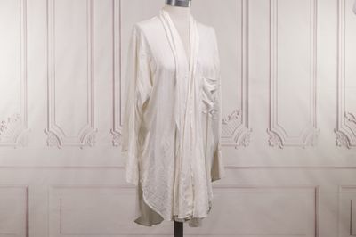 une robe blanche posée sur un pied de mannequin dans une pièce