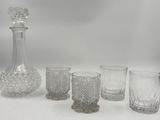 cinq verres et une carafe posés sur une table