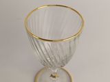 a glass with a gold rim sitting on a white surface