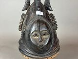 a close up of a metal mask on a stand on a table