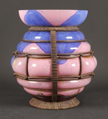 un vase rose et bleu posé sur un socle en bois