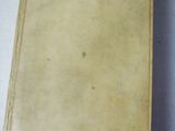 an old book sitting on top of a white table next to a cup