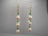 boucles d'oreilles ornées de perles et d'émeraudes, exposées dans une vitrine
