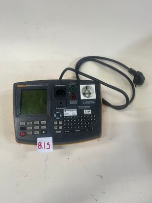 une image représentant une calculatrice posée sur une table, à côté d'un chargeur