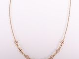 un collier en or orné de pierres roses sur fond blanc