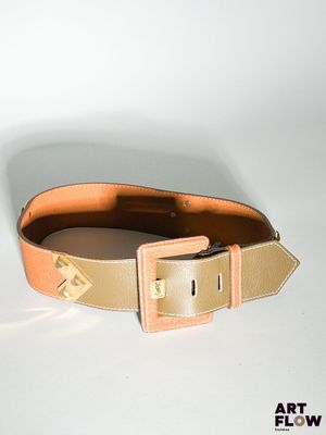 une ceinture munie d'une boucle, posée sur une surface blanche