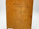 an old wooden box with writing on it sitting on a white surface