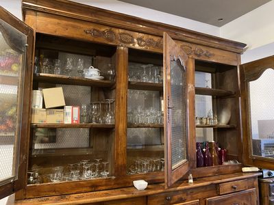 a wooden china cabinet with a glass door on top of it
