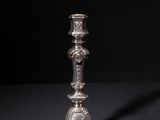 a silver candle holder on a black surface with a black background