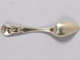 a silver spoon with a diamond on it on a white surface