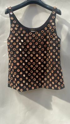 a black top with gold studding on it sitting on a hanger