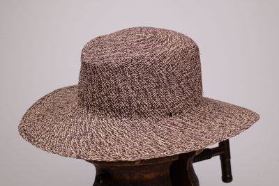 Le chapeau est marron et blanc, avec une bande noire.