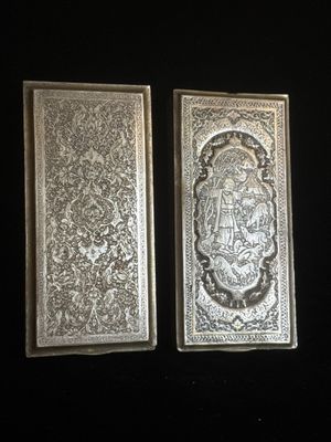 deux plaques métalliques argentées sur fond noir, l'une représentant un lion et l'autre un lion