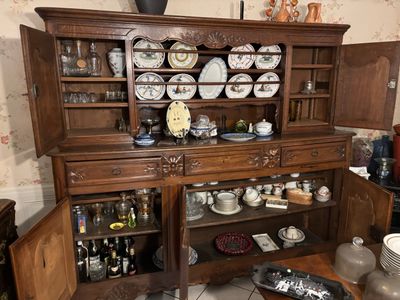 a wooden china cabinet with a lot of dishes on top of it
