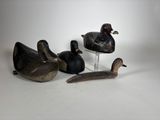 trois canards en bois et un oiseau posé sur un socle, le tout sur une surface blanche