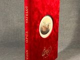 Le livre est rouge et il y a sur la couverture l'image d'un homme avec un chapeau.