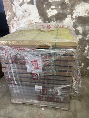 une pile de livres emballés dans du plastique, posée par terre
